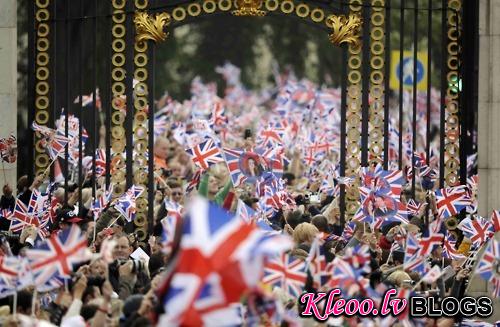 People wave British flags outside Buckingham Palace during the wedding of Britain